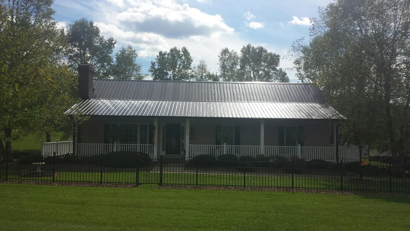 Gray metal roof on a brick ranch with a full width front porch — Gutter Guard Installation work by our crew in Newton